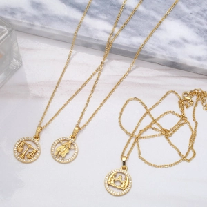 Gros plan de colliers dorés avec pendentifs zodiaque Balance Vierge et Gémeaux sertis