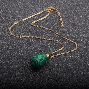 Gros plan d'un pendentif en malachite en forme de goutte sur une chaîne dorée brillante