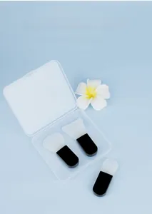Three silicone face mask brushes with black handles in a clear travel case on blue