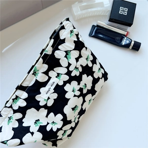 Macro view of floral canvas makeup pouch with green accents and simple wish label