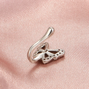 Macro shot of silver butterfly faux nose ring with crystals on pink silk background