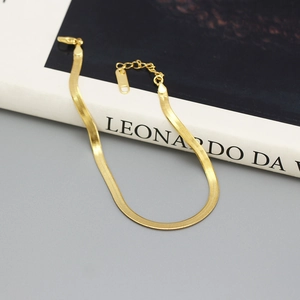 Detail of a golden flat snake bone bracelet with lobster clasp and extension chain