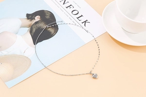 Close-up of elegant silver heart pendant necklace on minimalist lifestyle background