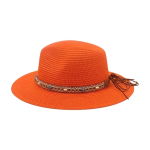 Détail d'un chapeau de paille orange avec bande perlée bohème et pompon en cuir élégant