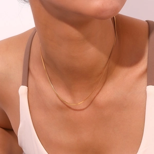 Polished 18K gold plated stainless steel snake chain necklace worn on a woman neck