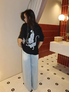 Back view of black t-shirt featuring a white leopard art print on the back with denim jeans