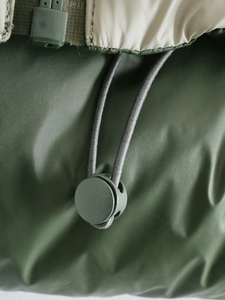 Detailed macro view of the green windproof fabric with adjustable drawcord and toggle