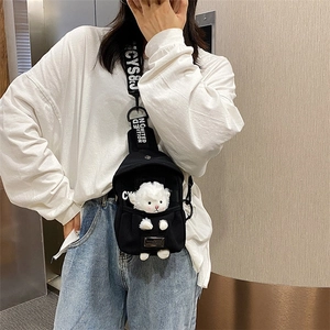 Close-up of black canvas chest bag featuring a plush lamb doll and lettered strap details