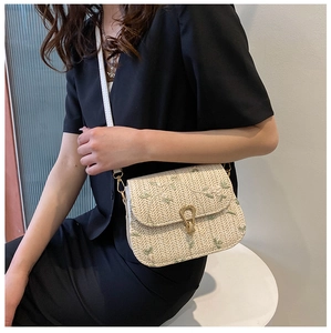 Detail of hand-woven crossbody bag with green floral embroidery and gold metal clasp