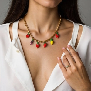 Golden beaded necklace featuring colorful fruit pendants on a professional female model