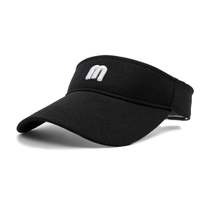 Detail of white 3D letter m embroidery on black sun visor hat with cotton texture