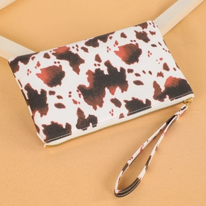 Close-up of cow print long wallet featuring gold zipper detail and matching wrist strap