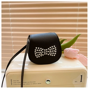 Détail d'un sac bandoulière enfant en cuir noir avec un nœud en perles blanches