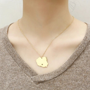 Detailed view of a gold Poland map necklace with heart cutout worn by a model