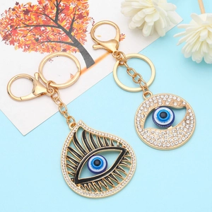 Golden Evil Eye keychains with sparkling rhinestones on blue decorative background