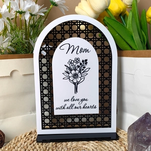 Detail of white acrylic Mom plaque with floral print and black wooden base decoration