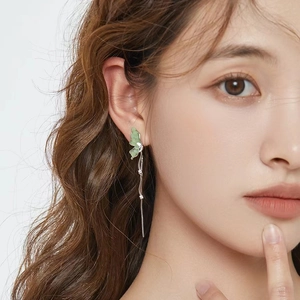 Close-up of S925 silver butterfly drop earring with green crystal and long tassels on model