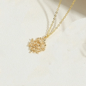 Macro detail of 14K gold plated branch style circular hollow pendant on elegant chain