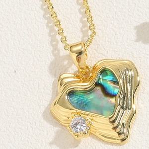 Macro detail of gold heart pendant with iridescent abalone shell and sparkling zircon
