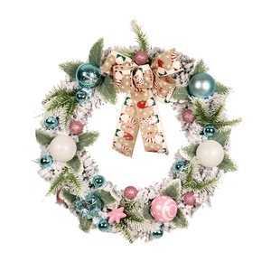 Flocked PVC Christmas wreath with blue and pink ornaments and a burlap bow on white background