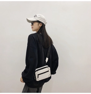 Detailed close-up of a white suitcase-style crossbody box bag with a black fabric strap