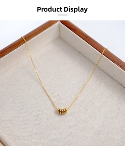 Detailed view of minimalist gold titanium necklace with five rings pendant on wood tray