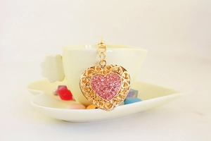 Close-up of golden heart keychain with pink rhinestones inside a heart-shaped saucer