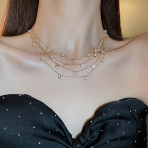 Detail einer mehrlagigen Goldkette mit klaren Zirkonia-Anhängern an einem Modell