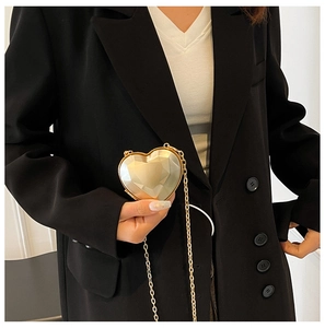 Close-up of golden heart-shaped evening bag with geometric facets and metal chain
