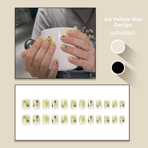 Short square press-on nails in translucent yellow with star patterns and small rhinestones