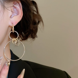 Detail shot of geometric layered hoop earrings with diamond-encrusted studs on a model