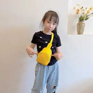 Minimalist bright yellow kids chest bag with adjustable strap worn across a black t-shirt