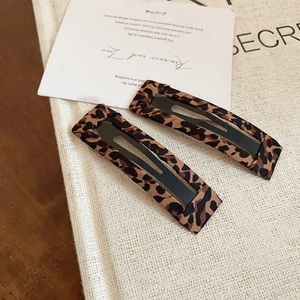 Dettaglio di fermagli per capelli con stampa leopardata su tessuto beige testurizzato