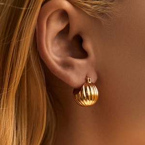 Close-up of chunky gold ridged hoop earrings featuring a vintage textured croissant design