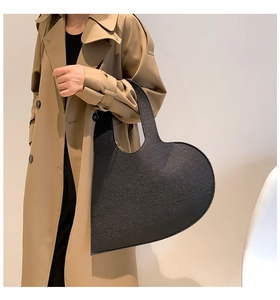 Detail of heart-shaped black felt handbag showing thick material and precise stitching