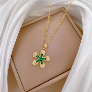 Detailed view of flower pendant necklace with green gems on a luxury jewelry box