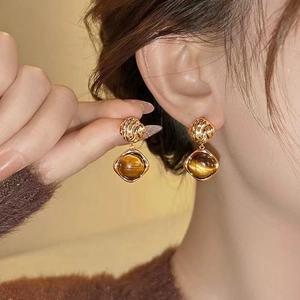 Vintage geometric gold drop earrings with brown tiger eye stone on female model