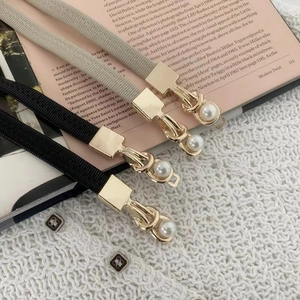 Close-up of slim elastic belts with gold metal buckles and elegant pearl inlay detailing