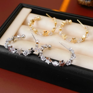 Close-up of gold and silver C-shaped star earrings with cubic zirconia in a jewelry box