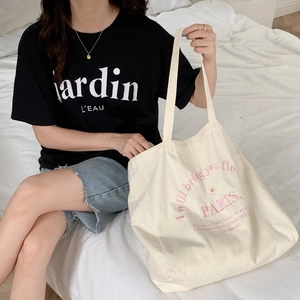 Detail of white canvas tote bag with pink floral Paris embroidery and text
