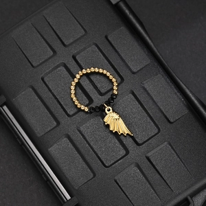 Macro detail of elastic beaded ring featuring golden wing charm and black faceted beads