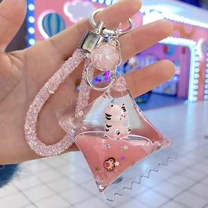 Detail of pink liquid sand keychain with white tiger mascot and glitter stars