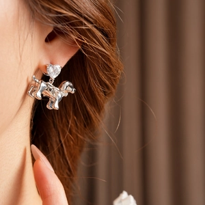 Close-up of heart-shaped crystal dog stud earring on model with polished silver finish