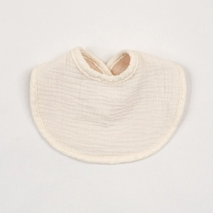 Detailed close-up of soft beige cotton baby bib showing absorbent crinkle muslin texture