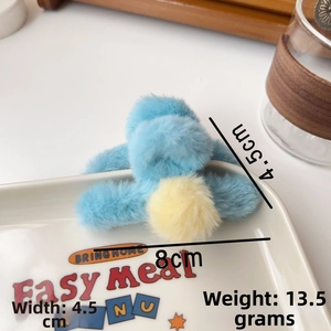 Detail shot of a small plush blue hair claw with yellow pom pom, 4cm width, for side hair