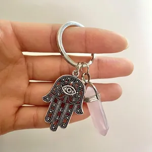 Detail of silver Hamsa Hand keychain with Evil Eye and pink crystal hexagonal pillar