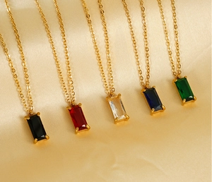 Row of gold titanium steel necklaces with colorful rectangular zircon pendants on silk