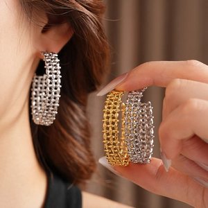 Close-up of wide braided C-shape hoop earrings in polished gold and silver finishes