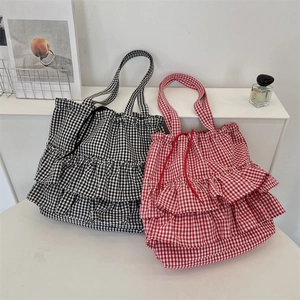Detail of plaid canvas tote bags with ruffle trim and drawstring closure in two colors