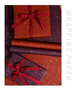 Detail of dark red and purple gift wrapping paper with elegant gold and silver foil flakes